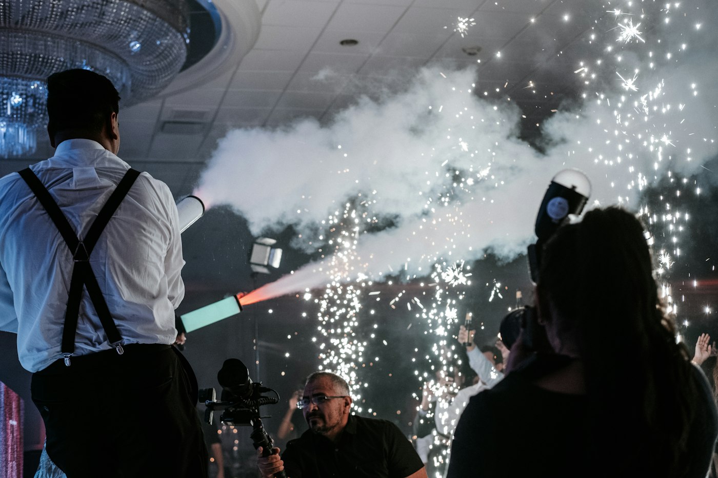 Cold spark fountains erupting on a dance floor with fog and CO2 effects under a chandelier